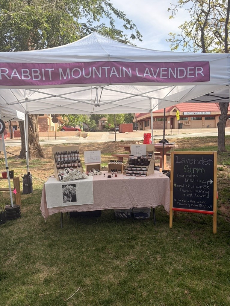 The Rabbit Mountain Lavender market tent, set up with products on the table and a hand-lettered sign